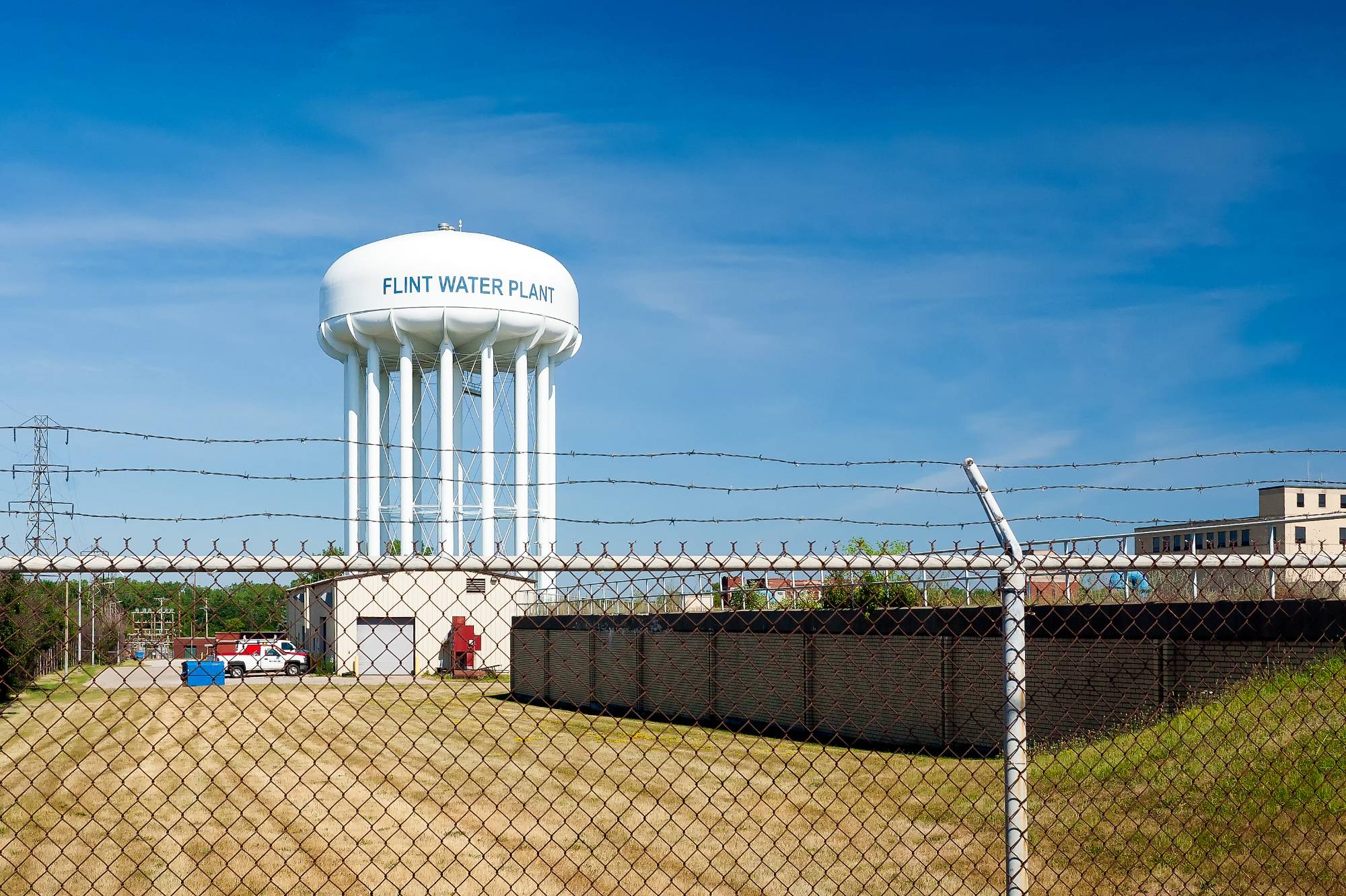 A water tower surrounded by barbed wire in Flint, Michigan. Photo by George Thomas under Creative Commons licensing.